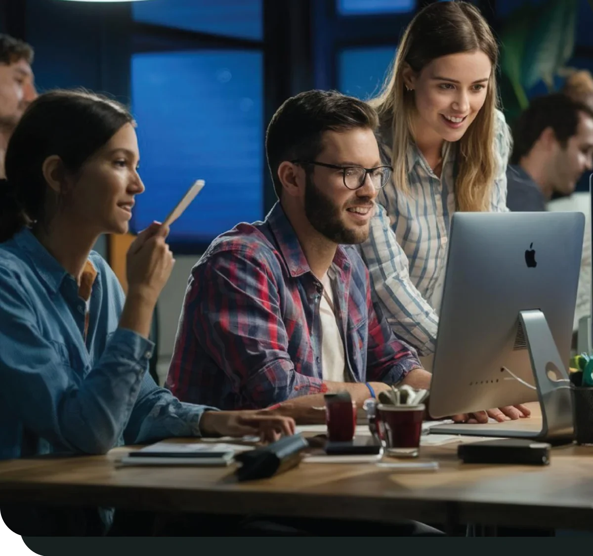 Team of professionals collaborating while working on a computer in an office.